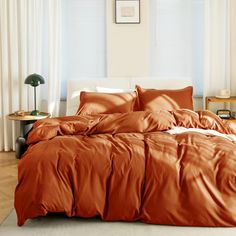 a bed with an orange comforter and pillows