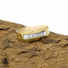 a yellow gold ring with three baguettes set in the center on top of a rock