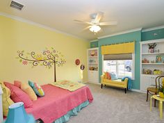 a child's bedroom decorated in pastel colors with a tree painted on the wall