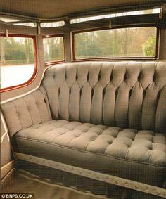 an old couch sitting in the back of a car with windows on each side and no one inside