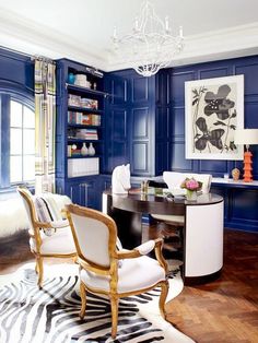 a living room with blue walls and white furniture in the center, along with zebra rugs on the floor