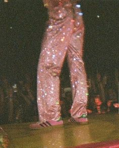 a person standing on top of a stage with their feet in the air while wearing shiny pants