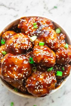 a bowl filled with sticky sesame cauliflower and topped with green onions