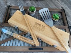 a bamboo cutting board with utensils and knives on it, next to a potted succulent