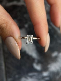 a woman's hand holding an engagement ring with a diamond on the middle finger