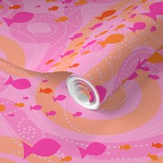 a pink and orange wallpaper with fish on it's side, next to a roll of toilet paper