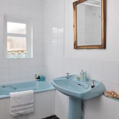 a bathroom with a sink, mirror and bathtub in blue color on the wall