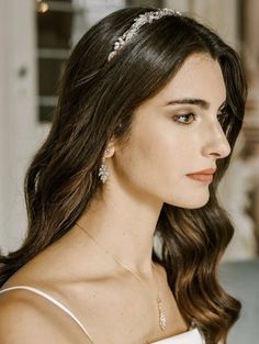 a woman in a white dress wearing a tiara with pearls and crystals on it