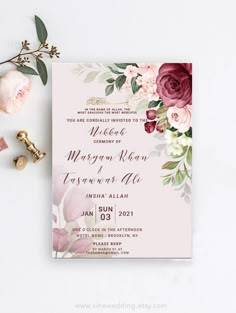 a wedding card with flowers and greenery on it