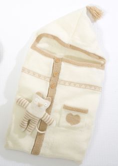 a white knitted baby sleeping bag with a teddy bear on it