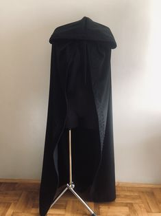 a black cape sitting on top of a wooden floor