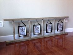 three framed pictures hang on a shelf in the middle of a room with hard wood flooring