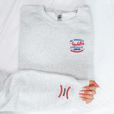 Welcome to my store! Cheer on your favorite player in style and comfort with our Gildan Heavy Blend sweatshirt, perfect for any baseball mom or sports enthusiast. This cozy crewneck is crafted from a soft, durable cotton-poly blend, making it an ideal choice for game days, casual wear, or simply showing your support for your little athlete. Personalize your sweatshirt with custom thread colors and a name on the sleeve for a unique touch that's all your own. Whether you're in the stands or out an Sporty Embroidered Sweatshirt For Sports Season, Sports Sweatshirt With Letter Embroidery In Cotton, Cotton Sports Sweatshirt With Letter Embroidery, Cotton Sweatshirt With Letter Embroidery For Sports, Cotton Sweatshirt With Embroidered Logo For Sports, Crew Neck Sweatshirt With Embroidered Logo For Sports, Sporty Sweatshirt With Embroidered Graphics For Game Day, Embroidered Crew Neck Sweatshirt For Sports Season, Cotton Sweatshirt For Sports Season