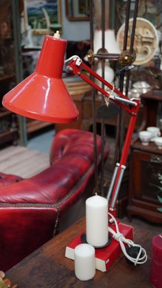 a red table lamp sitting on top of a wooden table next to a red couch