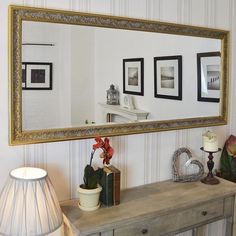 a mirror sitting on top of a wooden table next to a lamp and vases