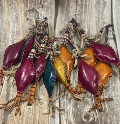 five leathers with tassels are on a wooden table and one is purple, the other red