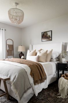 a white bed sitting in a bedroom on top of a carpeted floor next to a window