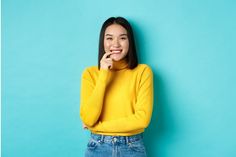 a woman in a yellow sweater is posing for the camera with her hand on her chin