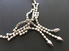 "Beautiful necklace signed Ledo - a company that created high quality jewelry during the 1950s. This necklace features a bow shaped centerpiece with tassels ending in pear shaped rhinestones. Great for a wedding or special occasion, this necklace has an elegant, well made feel. CONDITION/SIZE: In like new condition. This is a small necklace - just under 15\" long. Definitely choker length. LINKS: Looking for a VINTAGE NECKLACE, but this isn't the one? I have more here: https://etsy.me/2WVkYTs Lo Vintage Hand-set Jewelry For Formal Occasions, Vintage Hand Set Jewelry For Formal Occasions, Vintage Rhinestone Jewelry For Formal Occasions, Vintage Formal Jewelry With Rhinestones, Vintage Hand Set Evening Jewelry, Retro Silver Necklace For Evening, Vintage Adjustable Jewelry With Rhinestones, Vintage Rhinestone Adjustable Necklace, Retro Rhinestone Jewelry For Gifts