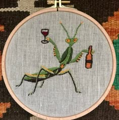 a cross - stitch picture of a praying mantissa with a glass of wine