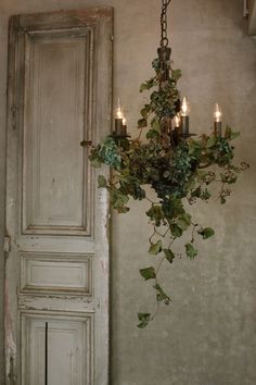 a chandelier hanging from the side of a wall with ivy growing on it