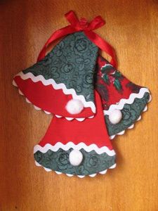 two christmas bells are hanging on a wooden table with red and green ribbon around them