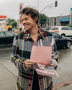 a man holding a pink piece of paper in his hand and smiling at the camera