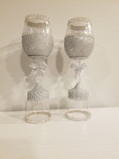 two crystal goblets with bows on them sitting next to each other in front of a white wall