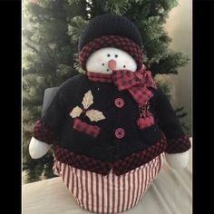 a stuffed snowman sitting in front of a christmas tree