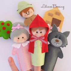 a hand is holding several small felt dolls in different colors and sizes, including one with a red hood