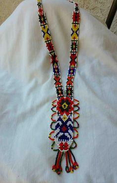 "This long necklace is composed of tiny multicolored beads that are in a narrow formation along neck, then get wider towards the bottom. Main beaded colors are red, blue, orange, and yellow. Sunburst loops near bottom with a fringe of six beaded rows hanging. No clasp or closure, this handmade piece goes right around neck. In good vintage condition. Any questions, Please inquire & Thanks for looking! measures total length- 18\" bottom width- 2 & 1/4\"" Red Southwestern Beaded Necklace, Southwestern Style Red Necklace For Festivals, Multicolor Hand-strung Beaded Necklace For Festivals, Multicolor Hand-strung Southwestern Beaded Necklaces, Hand-strung Multicolor Necklaces For Festivals, Multicolor Hand-strung Necklaces For Festivals, Colorful Traditional Beaded Necklaces For Festivals, Handmade Multicolor Southwestern Beaded Necklaces, Handmade Southwestern Multicolor Beaded Necklaces