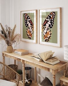 two framed butterfly pictures hang on the wall above a wooden table with books and plants