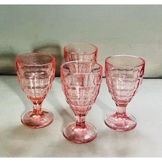 three pink glass goblets sitting next to each other