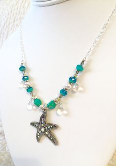 "Sparkling \"Star of the Sea\" beaded silver chain necklace featuring gorgeous 1 1/4\" x 1 3/8\" rhinestone starfish antique silver pendant. Surrounding the charm two-color Aqua designer Czech glass beads, lovely white Swarovski crystal pearls, turquoise Czech table cut beads, wire wrapped iridescent Czech glass teardrops, Czech vitrail (rainbow iridescent) beads, pewter and silver spacer beads. All strung on a pretty sparkly Sterling silver plate cable chain with unique easy to use handmade sil Bohemian Silver Necklace With Starfish Charm, Bohemian Silver Jewelry With Starfish Charm, Beach Jewelry In Silver With Rhinestones, Silver Rhinestone Beach Jewelry, Beach Silver Jewelry With Rhinestones, Silver Rhinestone Jewelry For The Beach, Silver Beaded Ocean-inspired Jewelry, Ocean-inspired Silver Beaded Jewelry, Silver Starfish Charm For Jewelry Making