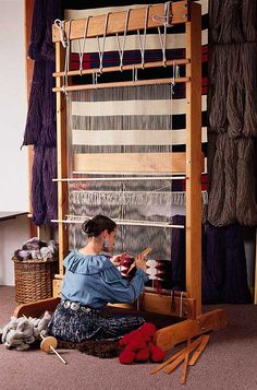 a woman sitting in front of an old weaving loom with yarn on the looms