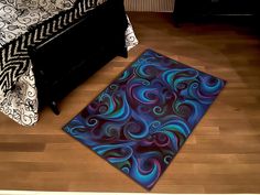 a blue and purple rug sitting on top of a wooden floor next to a bed