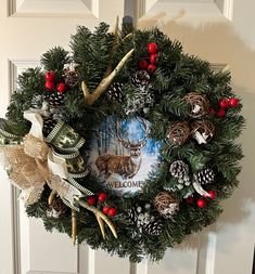 a christmas wreath hanging on the front door with deer and pineconis around it