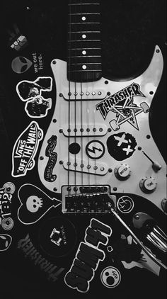 an electric guitar with many stickers on it's body and neck, in black and white