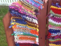 the colorful scarf is hanging on the wooden fence