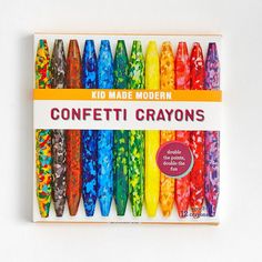 a box of colorful crayons sitting on top of a white table next to each other