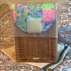 a wicker basket with tissue paper in it sitting on a patterned cloth covered tablecloth