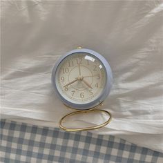 an alarm clock sitting on top of a bed with a checkered sheet behind it