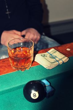 a pool ball sitting on top of a table next to a glass