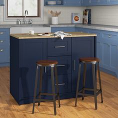 two stools sit at the center of a kitchen island in front of blue cabinets