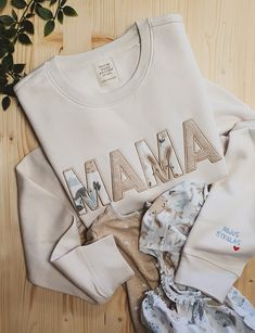 a white shirt with the word mama printed on it next to pajamas and a plant