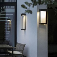 two lights on the side of a building next to a chair and table with a glass door