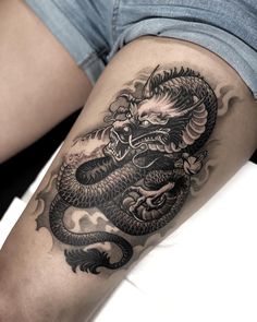 a black and white dragon tattoo on the thigh