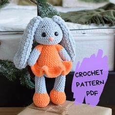 a crochet bunny sitting on top of a box next to a christmas tree