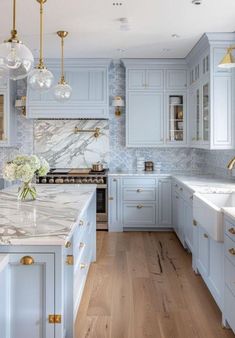 a kitchen with blue cabinets and marble counter tops, gold accents on the backsplash