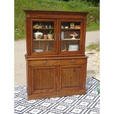 a wooden china cabinet sitting on top of a rug